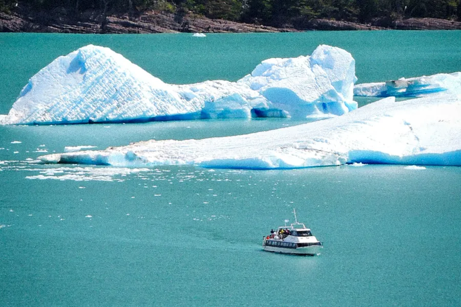 Embarcación de excursión navegando entre témpanos sobre el agua turquesa del lago